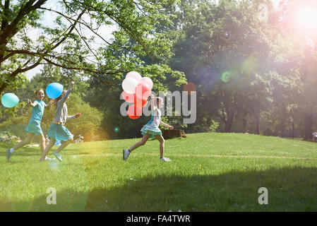 Le ragazze in esecuzione nel parco con palloncini, Monaco di Baviera, Germania Foto Stock