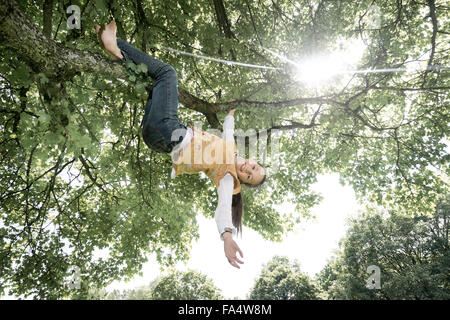 Ragazza appeso sulla struttura ad albero e sorridente, Monaco di Baviera, Germania Foto Stock