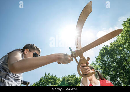 Basso angolo vista di due ragazze fingendo come pirati combattimenti con la spada in parco giochi avventura, Baviera, Germania Foto Stock