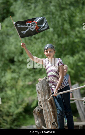 Ragazza in piedi su una nave pirata e mostrando bandiera pirata nel parco giochi avventura, Baviera, Germania Foto Stock