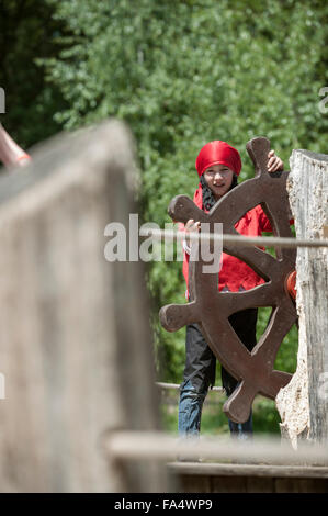 Ragazza fingendo come pirati tenendo il timone della nave nel parco giochi, Baviera, Germania Foto Stock