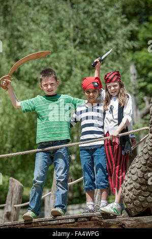 Tre amici travestiti da pirati giocano su una nave pirata nel parco giochi avventura, Baviera, Germania Foto Stock
