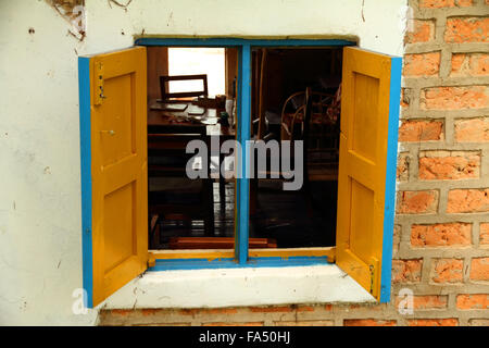 Guardare all'interno di un molto colorato di blu e giallo finestra costruito sul fianco di una casa di mattoni che lentamente si sta crollando. Foto Stock