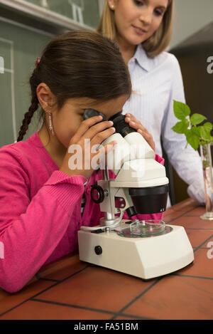 Studentessa con insegnante che guarda attraverso un microscopio, Fürstenfeldbruck, Baviera, Germania Foto Stock