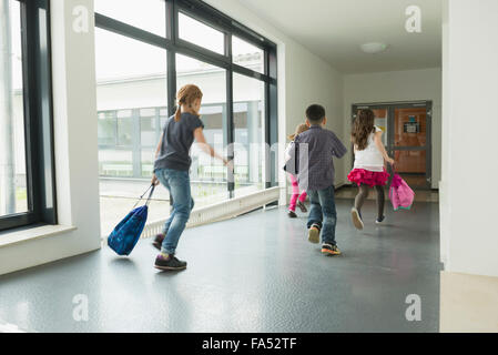 I bambini in esecuzione con le sacche per articoli sportivi nel corridoio della sala sportiva, Monaco di Baviera, Germania Foto Stock