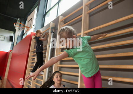 Le tre ragazze che esercitano sulla parete barre in grande palestra, Monaco di Baviera, Germania Foto Stock