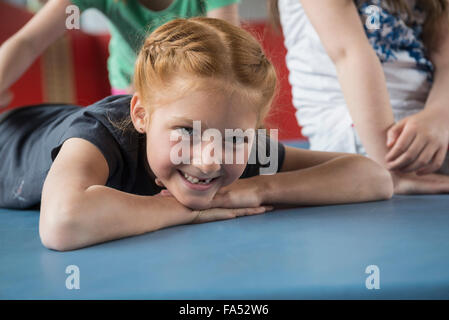 Ragazza distesa sul tappeto di esercizio nella grande palestra della scuola, Baviera, Monaco di Baviera, Germania Foto Stock