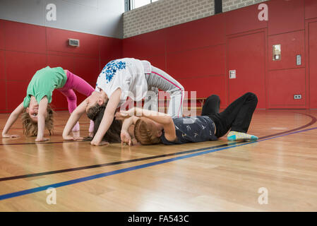 Le ragazze facendo posizione ponte yoga nella sports hall di Monaco di Baviera, Germania Foto Stock