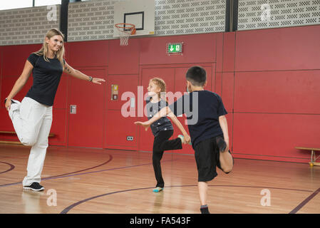 Insegnante con bambini fare esercizio nella sala sportiva, Monaco di Baviera, Germania Foto Stock