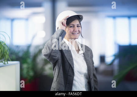 Ritratto di una imprenditrice sorridente in ufficio e indossando hardhat di Freiburg im Breisgau, Baden-Württemberg, Germania Foto Stock