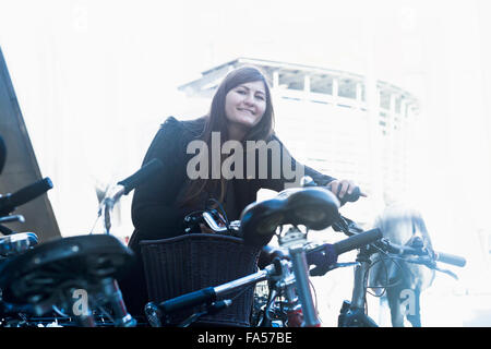 Giovane donna in piedi con la bicicletta nel parcheggio di Freiburg im Breisgau, Baden-Württemberg, Germania Foto Stock