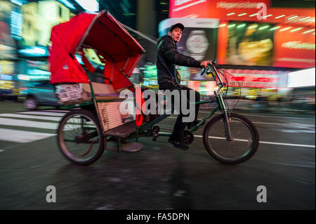 La città di NEW YORK, Stati Uniti d'America - 13 dicembre 2015: i passeggeri nel retro di un pedicab guardare fuori mentre passano attraverso Times Square. Foto Stock