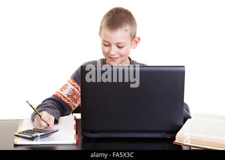 Diligente ragazzo seduto alla scrivania che sta facendo il suo dovere e lavorare con il computer portatile Foto Stock