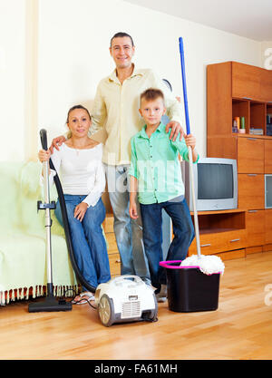 Ritratto di famiglia felice di tre con attrezzature per la pulizia in casa Foto Stock