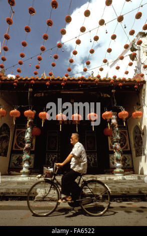 Uomo in sella ad una bicicletta in Chinatown di Melaka. Strade con lanterne rosse nel quartiere di Chinatown di Kampung Bakar Batu, Malacca o Melaka, Malaysia Foto Stock