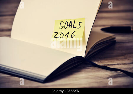 Primo piano di un aprire il blocco note con un bigliettino giallo con il testo obiettivi 2016 bloccato per una delle sue pagine vuote, con un filtro FEP Foto Stock