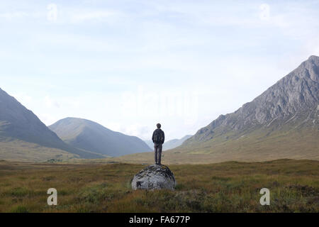 Uomo in piedi su una roccia che guarda il paesaggio di montagna, Highlands, Scozia, Regno Unito Foto Stock