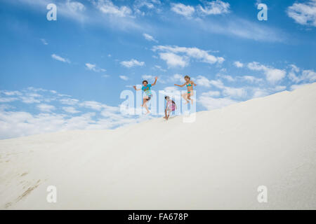 Un ragazzo e due ragazze jumping in dune di sabbia, Capo Verde, Australia occidentale, Australia Foto Stock