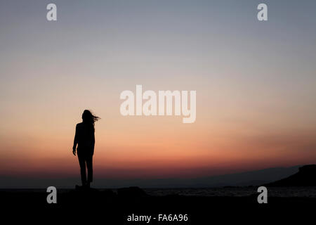 Silhouette di una donna in piedi all'aperto al tramonto Foto Stock