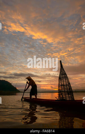 Silhouette di un uomo la pesca in lago, Thailandia Foto Stock