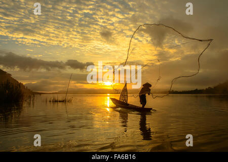 Silhouette di un uomo di gettare la pesca net, Lago Bangpra, Thailandia Foto Stock