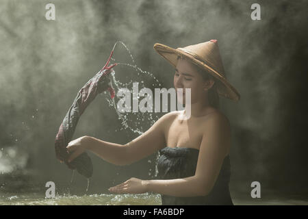 La donna a lavare i panni nel fiume, Thailandia Foto Stock