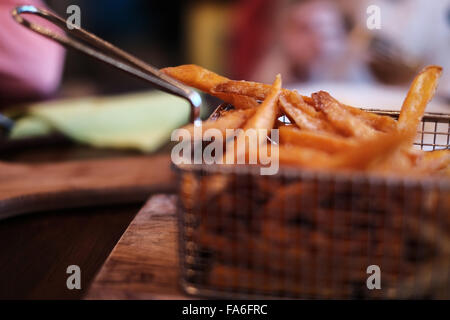 La patata dolce patate fritte in un cestello per frittura Foto Stock