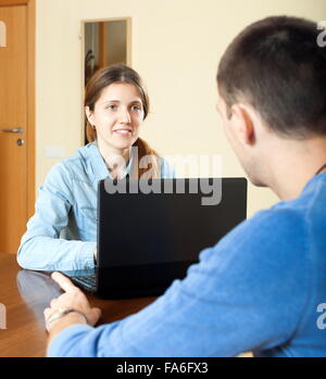 Uomo a rispondere alle domande del lavoratore di outreach con laptop in casa o in ufficio Foto Stock