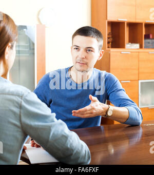 Uomo a rispondere alle domande del lavoratore di outreach con carta in casa Foto Stock