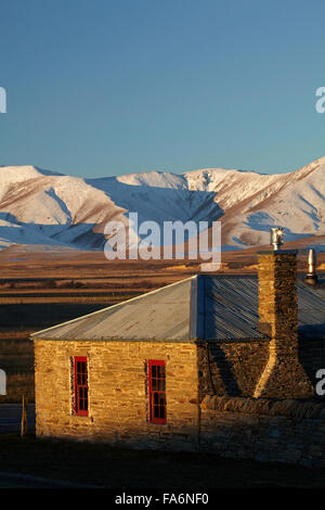 Storico cottage in pietra e gamma di Ida in inverno, Colline Creek, Maniototo di Central Otago, Isola del Sud, Nuova Zelanda Foto Stock