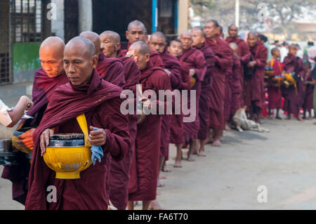 Monaco buddista in una lunga coda in Shwe Kyet ancora villaggio nella regione di Mandalay, Myanmar, è dato il cibo nella sua ciotola ALMS. Foto Stock