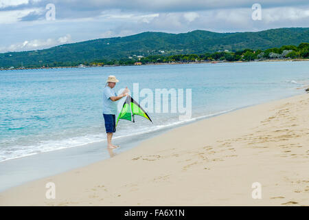 Un anziano uomo detiene un aquilone in preparazione al lancio sulla spiaggia a St. Croix, U.S. Isole Vergini americane Foto Stock