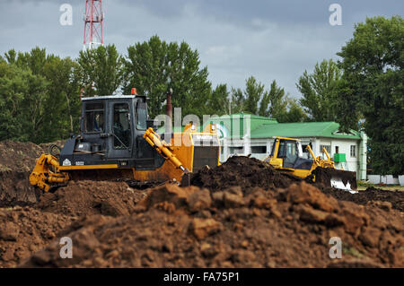 Due grandi bulldozer giallo si muove la massa in corrispondenza di un sito in costruzione Foto Stock