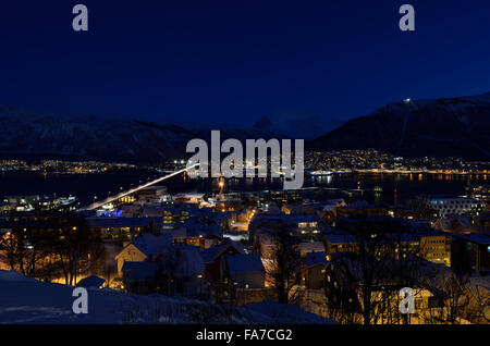 Tromso city in inverno nevoso notte con luce,traffico,fjord e movimento con il continente in background Foto Stock