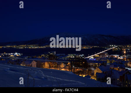 Tromso city in inverno nevoso notte con luce,traffico,fjord e movimento con il continente in background Foto Stock