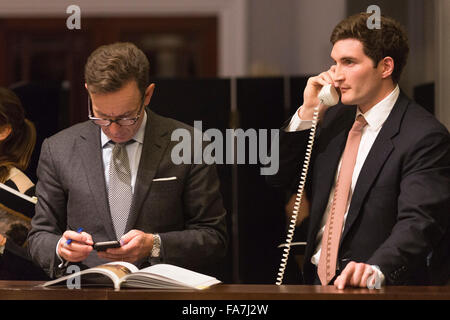 Gli agenti di vendita tenendo il telefono offerte. L'asta di dipinti dal Vecchio Maestro & British dipinti sera la vendita avviene a Sotheby's New Bond Street, Londra. Foto Stock