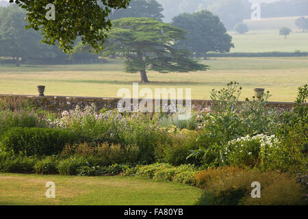 Piante erbacee terrazza giardino alla Killerton, Devon nel luglio mostra il cardo, urne cinerarie e parco al di là. La terrazza è stata suggerita da architetto Henry Protheroe nel 1900 e completato per le raccomandazioni di William Robinson nel 1905. Foto Stock