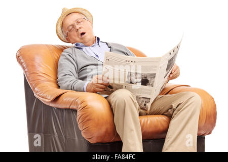 Studio shot di un anziano uomo di dormire su una poltrona e tenere un giornale nelle sue mani isolati su sfondo bianco Foto Stock