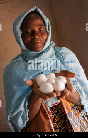 Una donna può contenere uova fresche previste dai suoi polli di Tengréla Village, Burkina Faso. Foto Stock