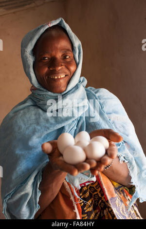 Una donna può contenere uova fresche previste dai suoi polli di Tengréla Village, Burkina Faso. Foto Stock
