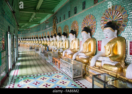 U min Thonze Pagoda statue di Buddha Sagaing Myanmar // SAGAING, Myanmar — Una fila curva di statue di Buddha si trova nella sala principale della Pagoda di U min Thonze (nota anche come Pagoda OoHminThoneSel), disposte nella caratteristica formazione a mezzaluna del tempio. La pagoda ospita 45 immagini uniche di Buddha che rappresentano i 45 anni di insegnamenti buddisti, costruite nella collina di Sagaing in un tempio artificiale ibrido. Originariamente fondata da re Tarabya i tra il 1327 e il 1335, l'attuale struttura risale alla ricostruzione di re Pagan min completata nel 1847 in seguito al devastante terremoto di Ava del 1839. U min Tho Foto Stock