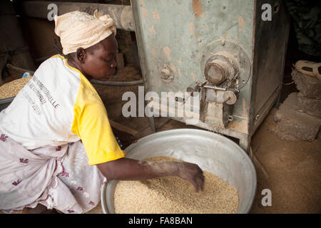 Il riso viene macinato prima di essere venduto ad un gruppo di donne dal centro di elaborazione in provincia Sourou, Burkina Faso. Foto Stock