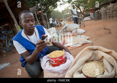 Una commodities acquirente utilizza la tecnologia telefonica mobile a confronto dei prezzi nei vari mercati in Burkina Faso, W. Africa. Foto Stock