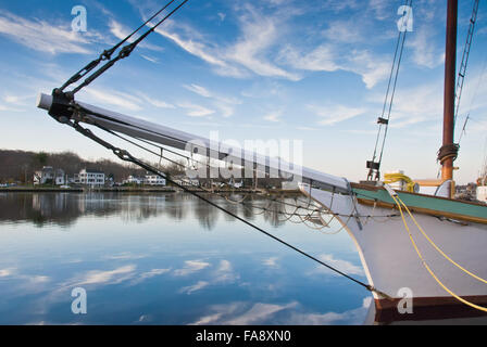 Bompresso di legno goletta a vela quayside sul fiume mistico, CT. Cielo blu brillante è specchiata ancora in acqua. Case coloniali. Foto Stock