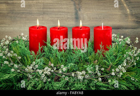 Avvento decorazione ramo di pino con tre rossi candele accese. Vacanze a sfondo Foto Stock