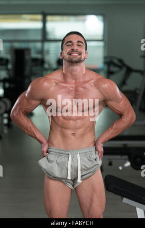 Awesome bodybuilder che mostra i suoi muscoli e in posa nella palestra Foto Stock