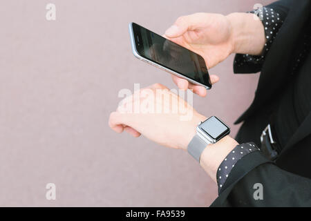 Imprenditore giapponese con smart indossabile guarda e lo smartphone Foto Stock