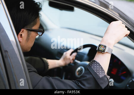 Uomo giapponese in auto con wearable smart watch Foto Stock