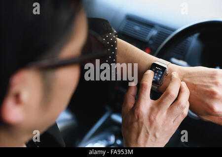 Uomo giapponese in auto con wearable smart watch Foto Stock