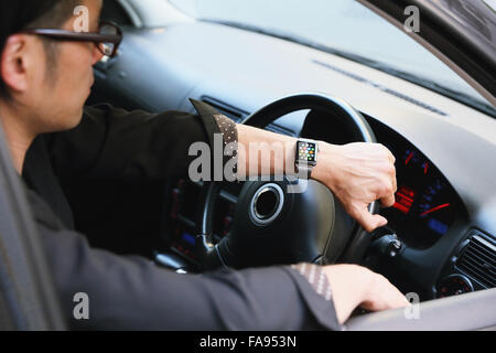Uomo giapponese in auto con wearable smart watch Foto Stock
